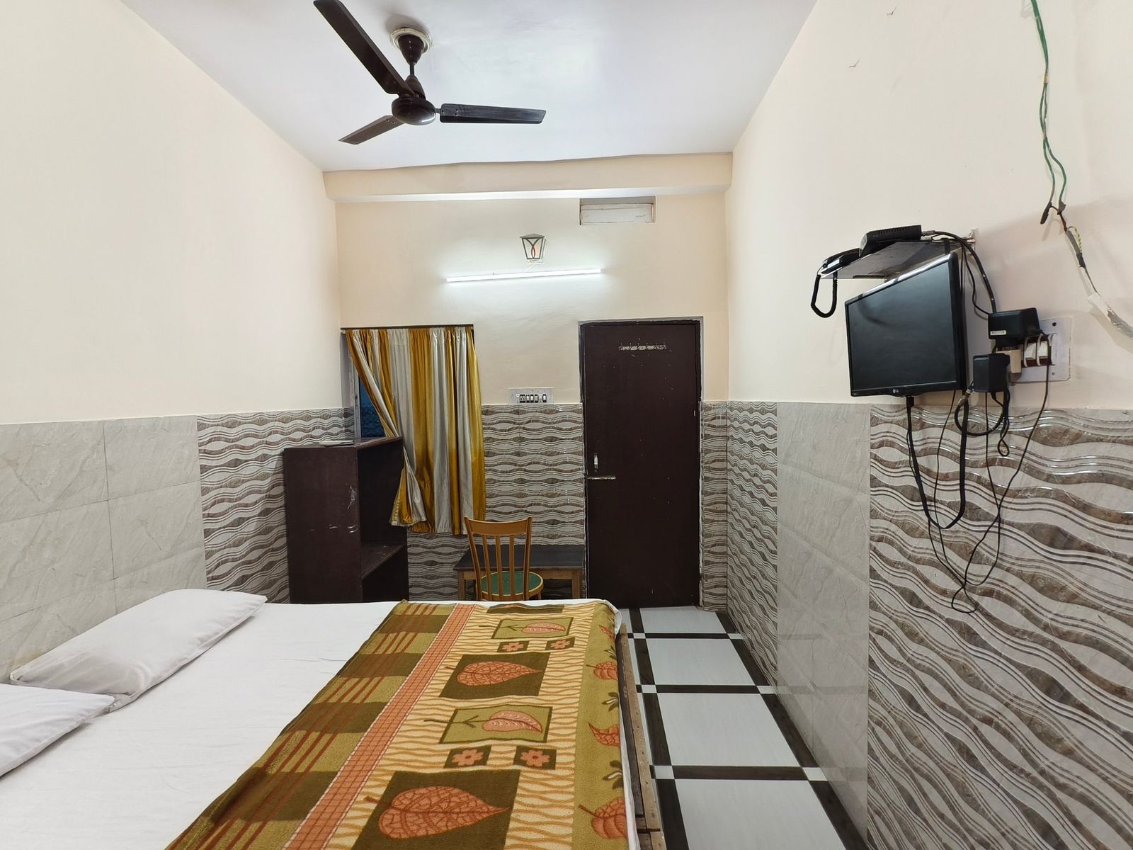 AC room with double bed, wall-mounted LED TV and tiled walls at Hotel Vijay, Rajgir