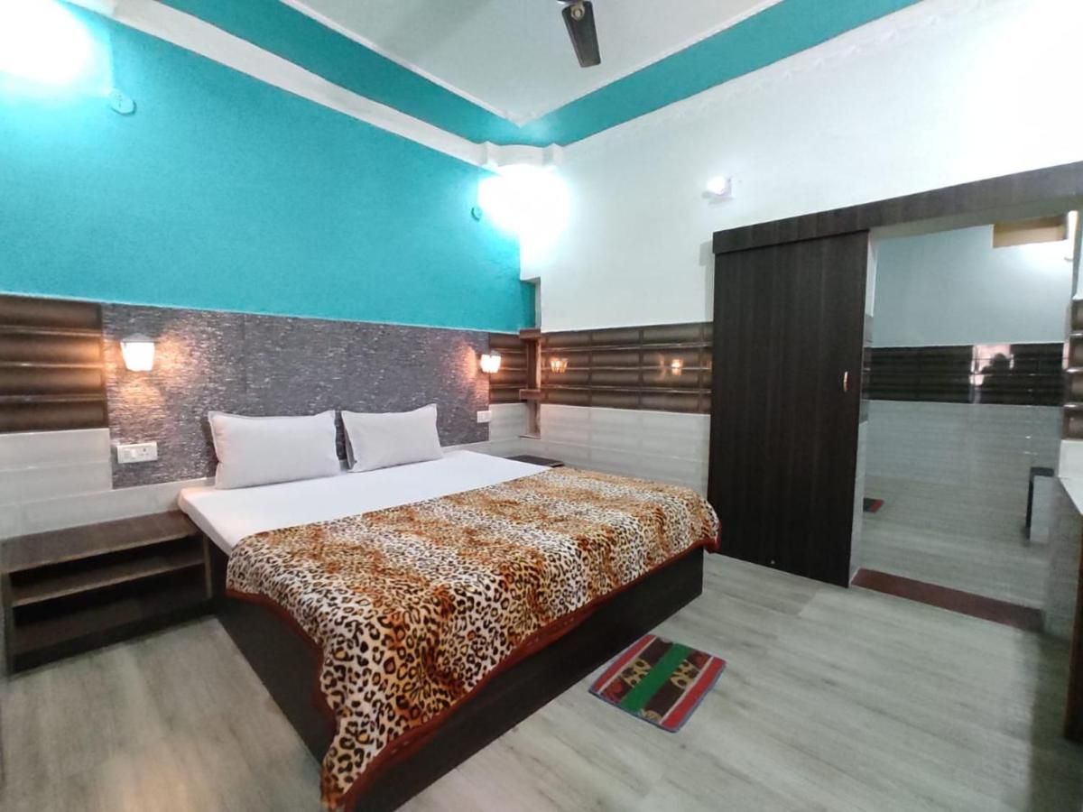 Family room with large double bed, teal feature wall and bedside lamps at Hotel Vijay, Rajgir