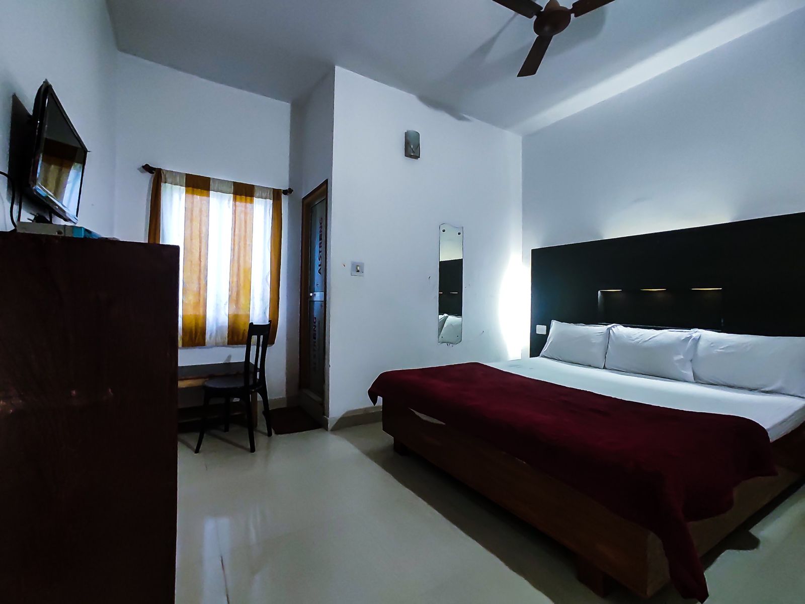 Guest room with double bed, dark headboard and wall-mounted TV at Hotel Vijay, Rajgir