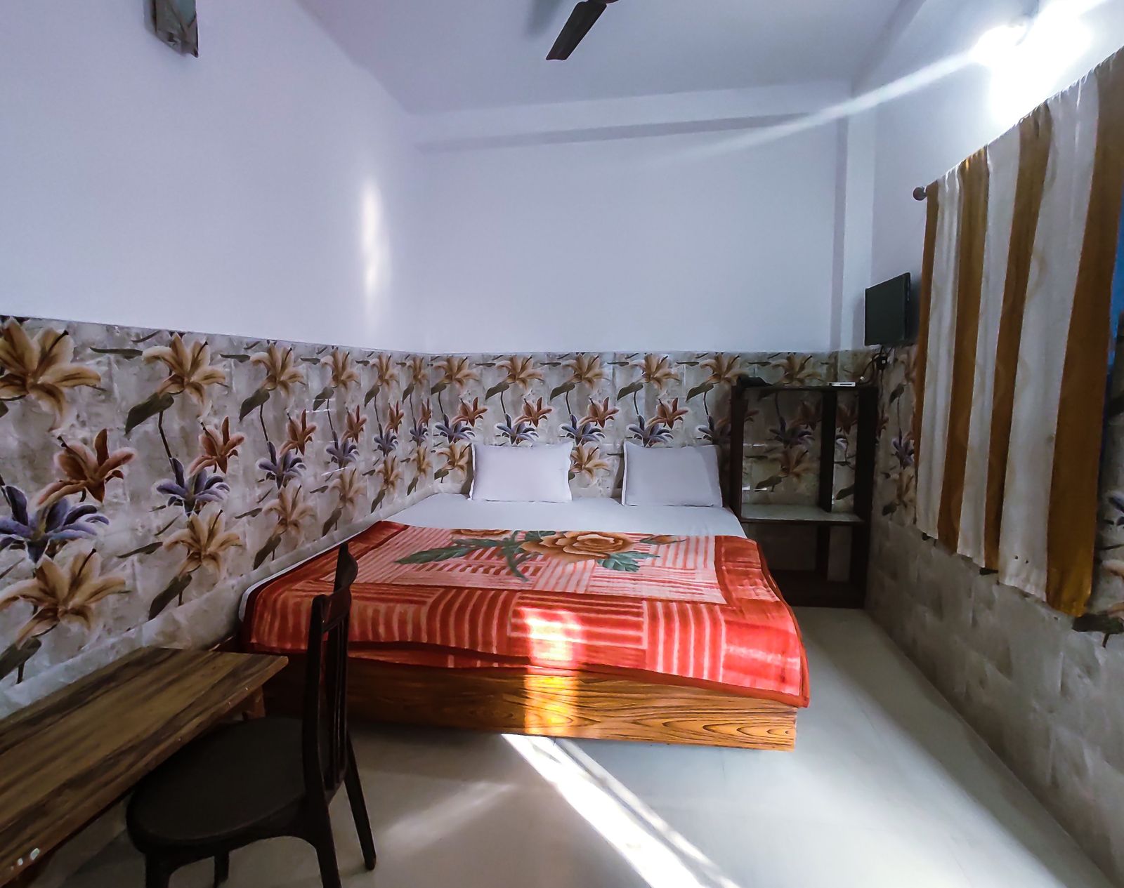 Guest room with double bed, desk and floral tiled wall at Hotel Vijay, Rajgir
