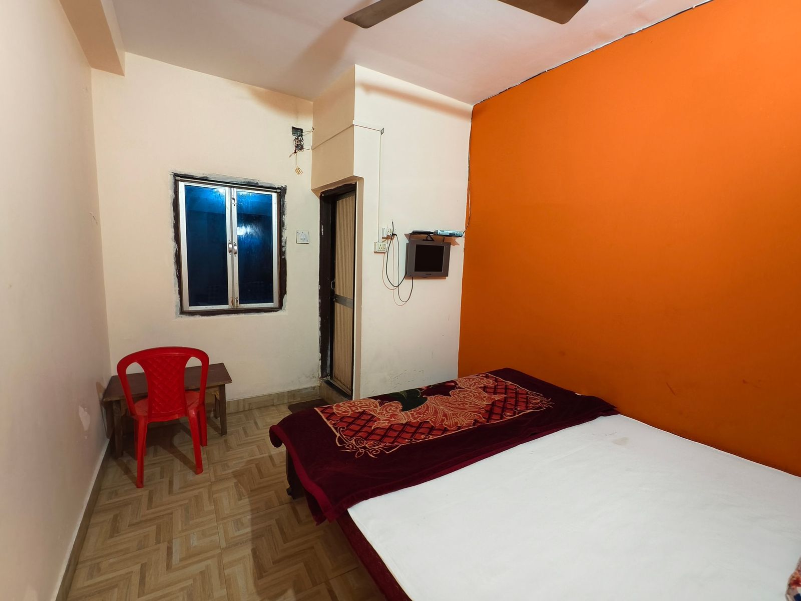 Guest room with window and orange feature wall at Hotel Vijay, Rajgir